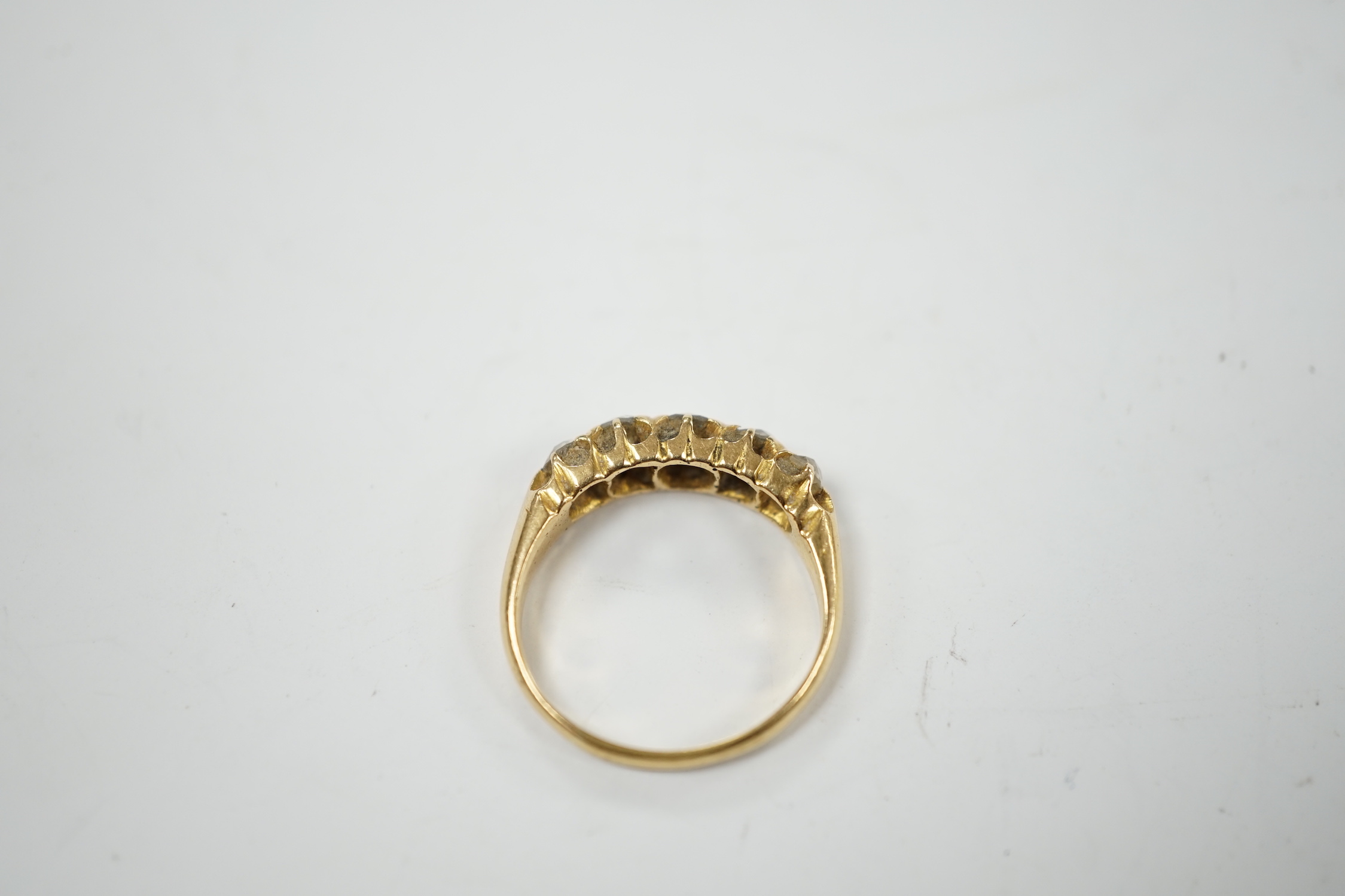 A late Victorian 18ct gold and graduated five stone diamond set half hoop ring, size L/M, gross weight 3.6 grams.